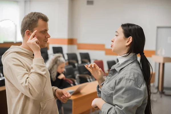 那个女孩和那个男人用手语说话。两个聋哑学生在大学课堂上聊天. — 图库照片