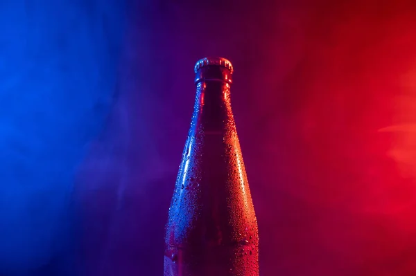 Стеклянная бутылка пива в голубом розовом тумане — стоковое фото