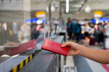 Kimliği belirsiz bir kadın havaalanı gişesinde pasaportunu veriyor..