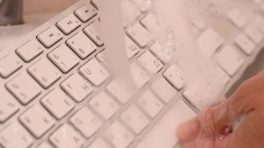 Beyaz bilgisayar klavyesini süngerle yıkayan kadın..