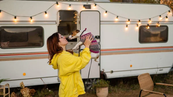 Kızıl saçlı beyaz kadın bir köpeğe sarılıyor ve bir karavanda yaşıyor. Karavanla seyahat et..