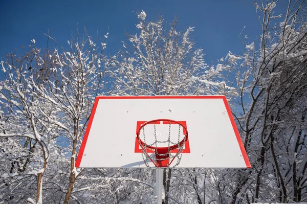 Баскетбольное кольцо в снегу зимой. — стоковое фото