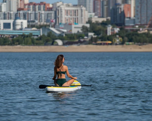 Femme caucasienne monte un conseil SUP sur la rivière dans la ville. Sport d'été. — Photo