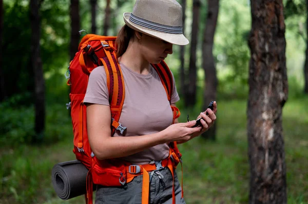 Молода біла жінка ходить пішки і використовує компас в лісі . — стокове фото