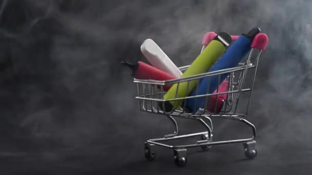 Einweg-Dämpfe in einem Einkaufswagen auf schwarzem Hintergrund. Moderne elektronische Zigaretten. — Stockvideo