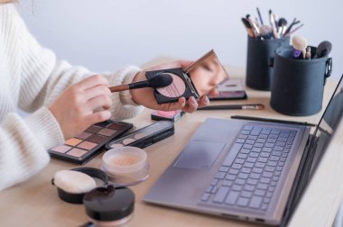 Çevrimiçi makyaj dersleri. Bir kadın laptopta kendini makyaj sanatçısı olarak eğiten bir video izliyor.