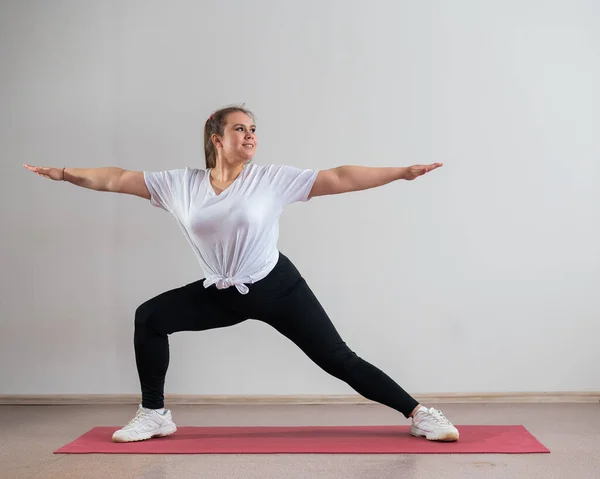 Ung fet kvinna gör flexibilitetsövningar på en vit bakgrund — Stockfoto