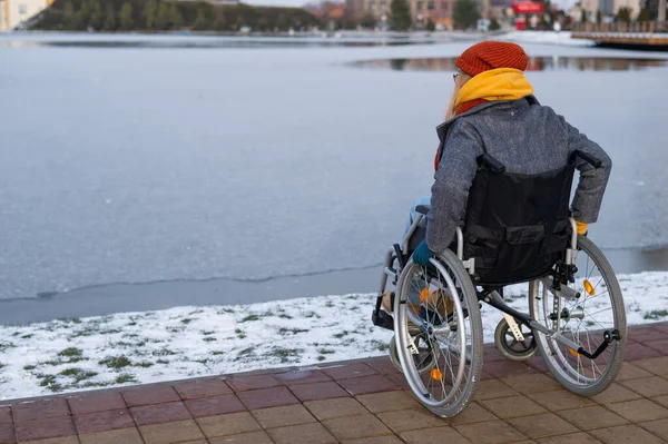 Caucasian woman in a wheelchair walks by the lake in winter. — 图库照片