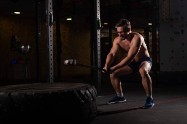 Beyaz bir adam spor salonunda araba lastiği itiyor.. 