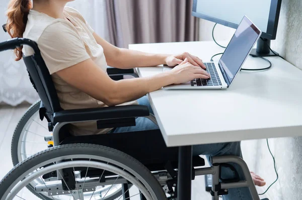 Mulher branca em uma cadeira de rodas digitando com um laptop de casa. Trabalho remoto para pessoas com deficiência. — Fotografia de Stock