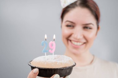 Mutlu kadın bir dilek diler ve 29. yaş günü pastasındaki mumları söndürür. Gülümseyen kız doğum gününü kutluyor.