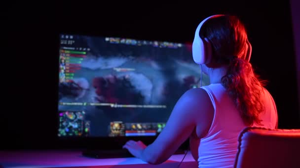 Visão traseira de uma mulher caucasiana jogando um jogo de computador em luz de néon no escuro. — Vídeo de Stock