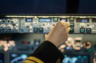 Bir pilotun yakın plan fotoğrafı. Bir uçak kontrol panelinin üzerinde..