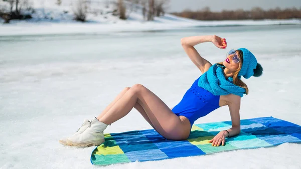 Beautiful caucasian woman in a swimsuit and a hat sunbathes on the snow. — Fotografia de Stock