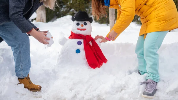 Två vita kvinnor gör en snögubbe. Vinternöje. — Stockfoto