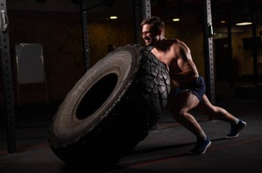 Beyaz bir adam spor salonunda araba lastiği itiyor.. 