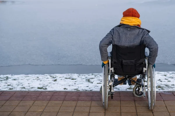 Donna caucasica in sedia a rotelle passeggiate al lago in inverno. — Foto Stock