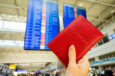 Havaalanı bilgi panosunun arka planında pasaportu olan bir kadın..