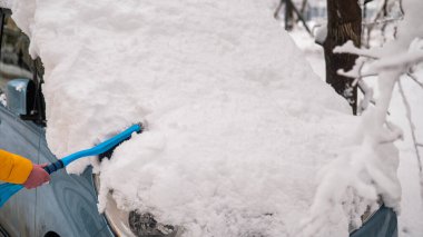 Beyaz kadın yeni yağmış kardan bir arabayı fırçalıyor.. 