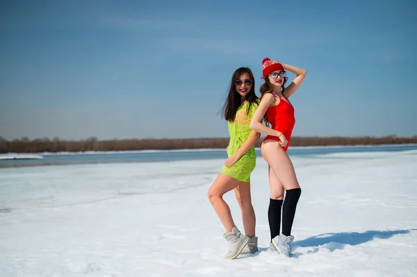 Two girlfriends in swimsuits walk along the shore of the frozen sea. — Stock Photo, Image