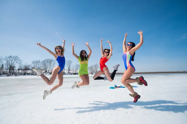 Quattro donne caucasiche in costume da bagno si divertono su una spiaggia innevata. Divertimento invernale. — Foto Stock