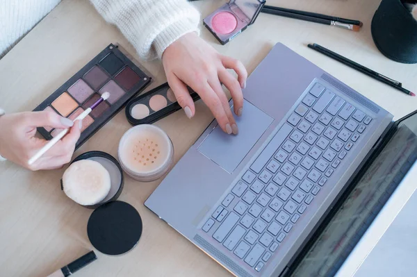 Uma mulher sem rosto assiste ao treinamento on-line de um artista de maquiagem profissional em um laptop. Ensino à distância — Fotografia de Stock