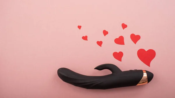 Black clitoral vaginal dildo and hearts on a pink background. Female vibrator as a gift for Valentines Day — Stock fotografie