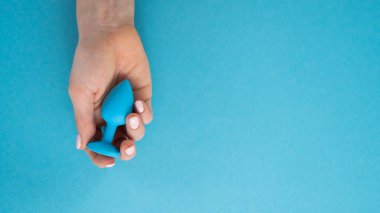 Mavi arka planda mavi anal tıpa tutan bir kadın var. Alternatif seks için yetişkin oyuncağı