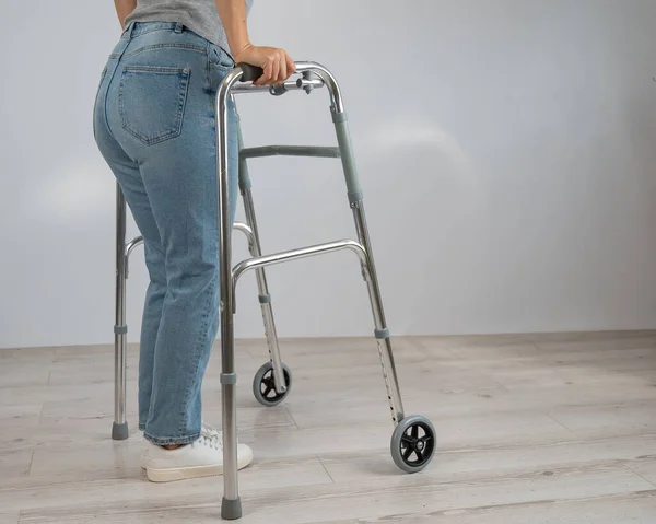 Close-up de pernas femininas com andarilhos. A menina caminha com a ajuda de equipamentos especiais. — Fotografia de Stock