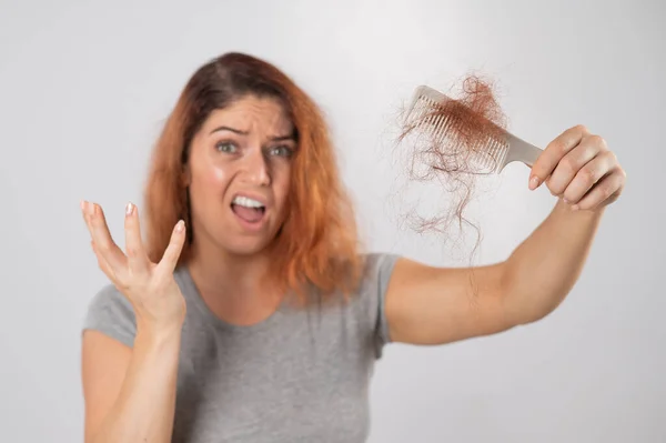 Tüyleri diken diken olmuş beyaz bir kadın elinde bir tutam saçla. Saç kaybı ve kadın saç dökülmesi.. — Stok fotoğraf