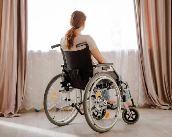 Caucasian woman in a wheelchair at the window. — Stock Photo, Image