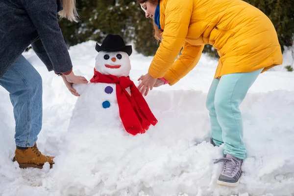 Två vita kvinnor gör en snögubbe. Vinternöje. — Stockfoto