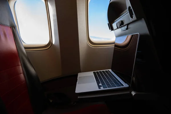 Ordenador portátil en una mesa plegable en un avión en clase económica. — Foto de Stock