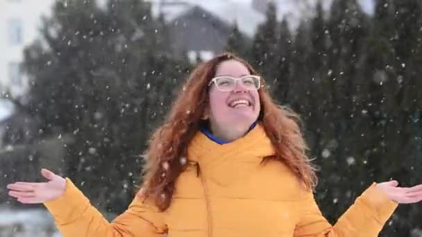 붉은 머리 백인 여성은 겨울에 기뻐하며 손바닥으로 눈송이를 잡는다. — 비디오