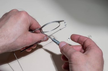 Gözlüklü burun pedleri. Erkek bir teknisyen kırık bardakları tamir ediyor.
