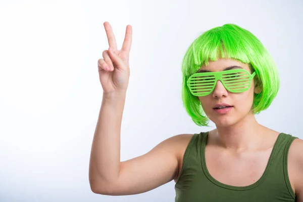 Joyeux jeune femme en perruque verte et lunettes drôles célébrant st patricks jour sur un fond blanc — Photo