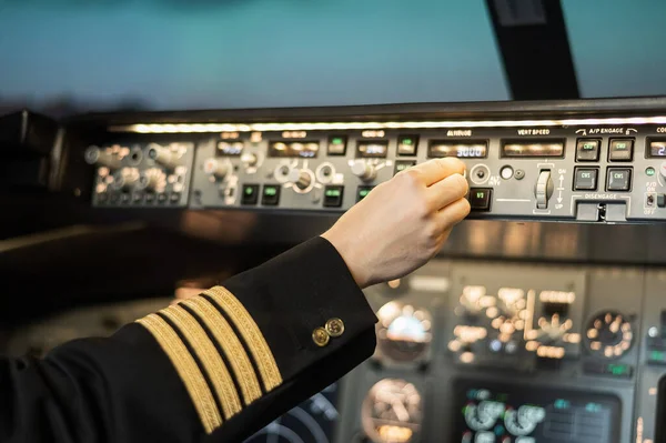 Close-up of a pilots hand on an airplane control panel.