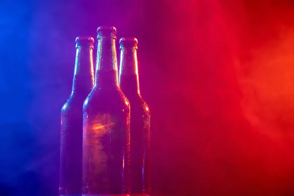Три бутылки пива в сине-розовом тумане. — стоковое фото