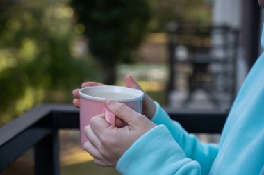 Balkonda sıcak bir şeyler içen bir kadın.. 