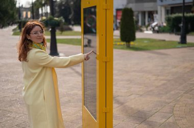 Açık havada dokunmatik bilgi panosu kullanan beyaz bir kadın.. 