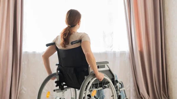 Mulher branca em uma cadeira de rodas na janela. — Fotografia de Stock