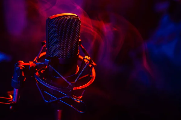 Professionele microfoon in rood blauwe rook op een zwarte achtergrond. — Stockfoto