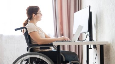 Tekerlekli sandalyedeki beyaz kadın laptopla çalışıyor.. 