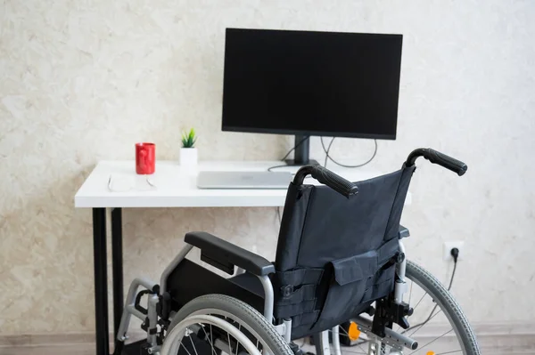 Local de trabalho para uma pessoa com deficiência. Cadeira de rodas na mesa com um computador. — Fotografia de Stock