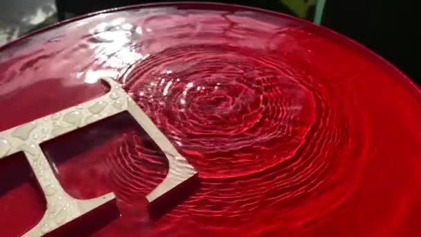 Close-up pioggia gocciola su uno sfondo rosso e lascia cerchi sull'acqua. — Video Stock