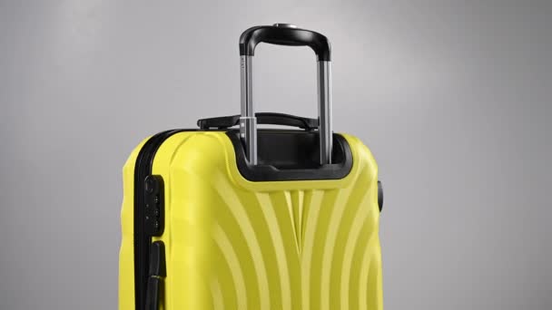 Κίτρινη βαλίτσα περιστρέφεται σε λευκό φόντο. — Αρχείο Βίντεο
