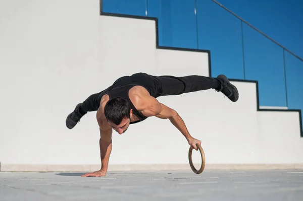 Siyah spor kıyafetli bir adam açık havada bir ringde akrobatik amuda kalkıyor.. — Stok fotoğraf