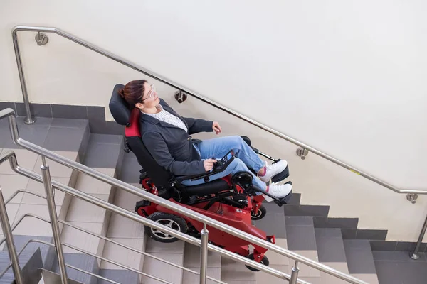Donna caucasica in sedia a rotelle bruco elettrico sale le scale. — Foto Stock