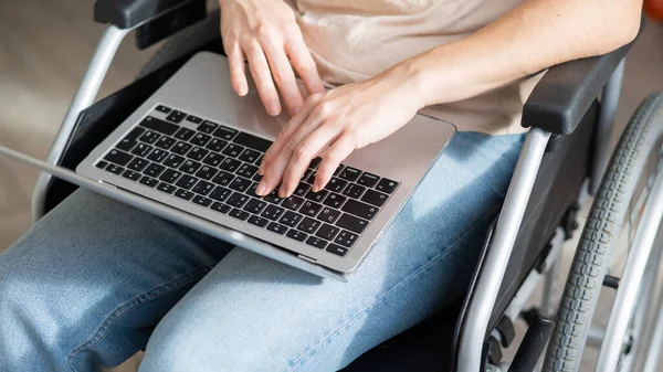 Uma mulher em uma cadeira de rodas usa um laptop. — Fotografia de Stock