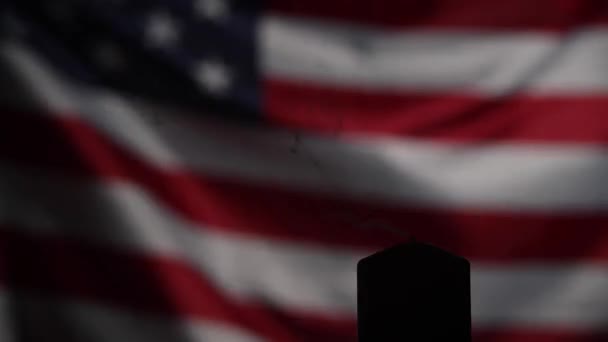 Uma vela extinta contra a bandeira acenando dos Estados Unidos da América no escuro. — Vídeo de Stock